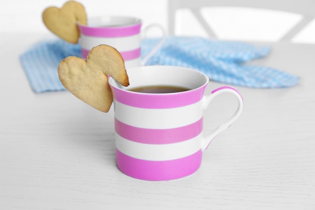 Galleta con forma de corazón en una taza de café en el primer plano de la mesa