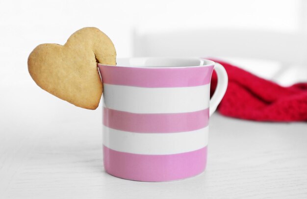 Galleta con forma de corazón en una taza de café en el primer plano de la mesa