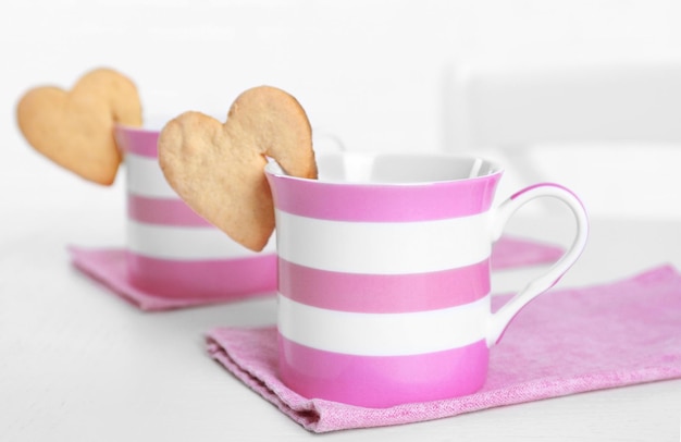 Galleta con forma de corazón en una taza de café en el primer plano de la mesa