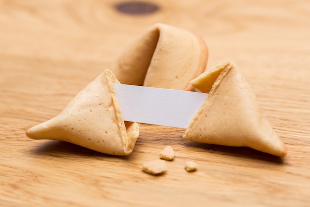 Una galleta de la fortuna abierta con una nota sobre el fondo de la mesa de madera. Tomada en estudio con una 5D mark III.