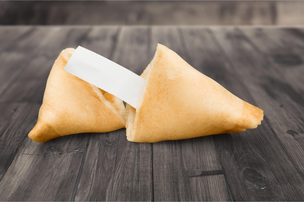 Galleta de la fortuna con hoja en blanco sobre fondo de madera