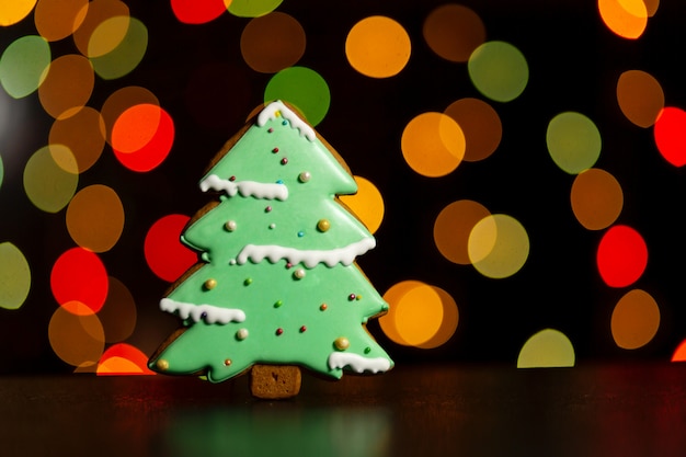 Galleta de jengibre de árbol de Navidad verde sobre luces de guirnaldas de colores defocused. Comida tradicional de navidad. Concepto de vacaciones de Navidad y año nuevo.