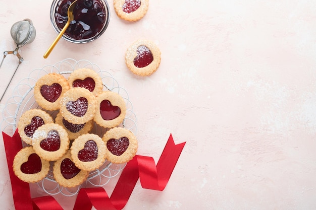 Galleta Linzer tradicional con mermelada de fresa y azúcar en polvo sobre fondo rosa hermoso Vista superior Postre dulce austriaco tradicional casero en el Día de San Valentín Concepto de merienda navideña