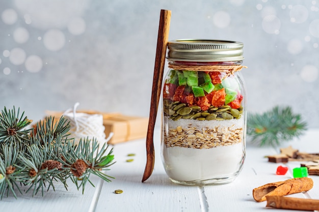 Galleta de Navidad mix jar. Ingredientes secos para cocinar galletas de Navidad en un frasco, fondo blanco. Concepto de comida navideña.