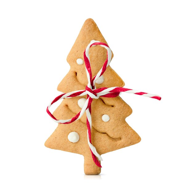 una galleta de pan de jengibre en forma de árbol de Navidad atado con un arco se encuentra en un blanco