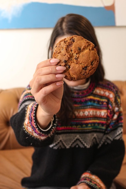 Foto galleta con trocitos de chocolate en la mano de una mujer