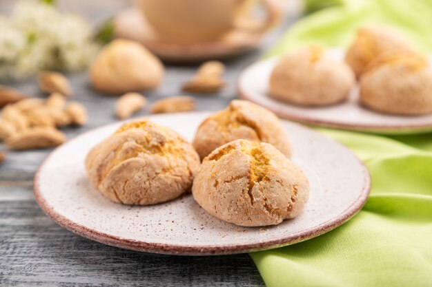 Galletas de almendra y una taza de café sobre un fondo de madera gris y textil de lino verde.