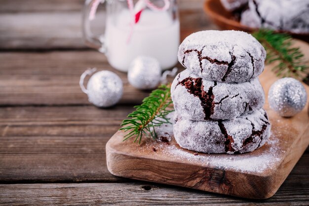 Galletas arrugadas de chocolate con glaseado de azúcar en polvo para navidad sobre fondo de madera