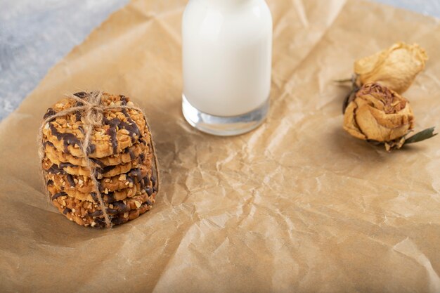 Galletas de avena bañadas en chocolate y una jarra de vidrio con leche.