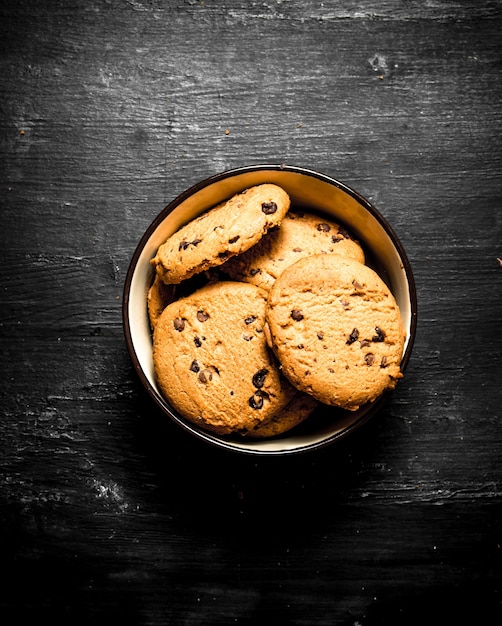 Galletas de avena en un bol. Sobre una mesa de madera negra.