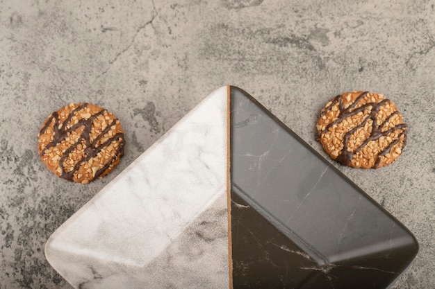 Galletas de avena caseras con nueces y recipiente vacío en piedra.