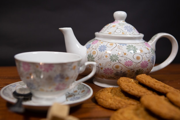 Galletas de avena caseras con una taza de té sobre un fondo de madera vieja