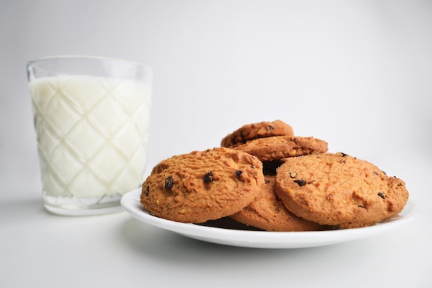 Galletas de avena caseras con trozos de chocolate de cerca, en el fondo un vaso de leche.