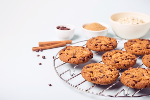 Galletas de avena con chispas de chocolate en una rejilla redonda para enfriar e ingredientes