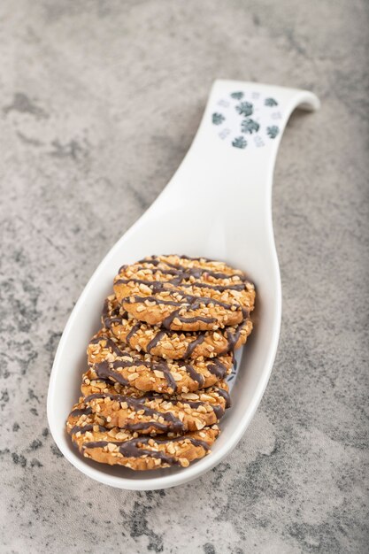 Galletas de avena y chocolate con nueces colocadas junto a una cuchara de cerámica.