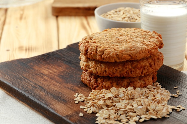 Foto galletas de avena con copos de avena y taza de leche en la mesa de madera