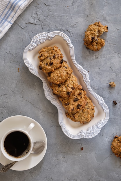 Foto galletas de avena fragantes en un plato con bordes calados en un primer plano de la mesa gris