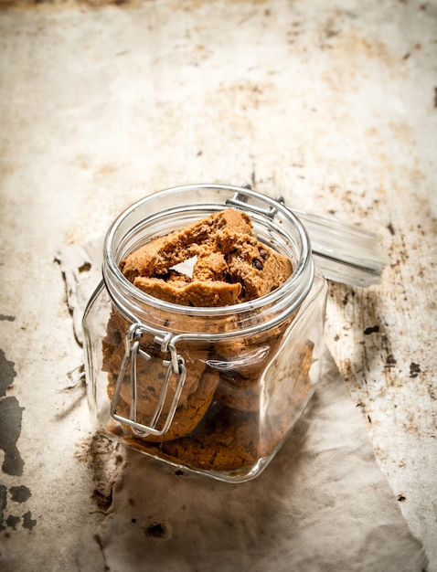 Galletas de avena en un frasco. Sobre una vieja mesa rústica.