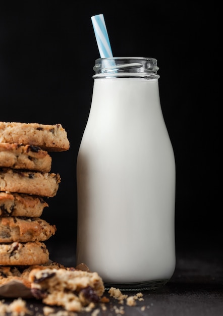 Galletas de avena orgánica casera con pasas y albaricoques y botella de leche en madera oscura