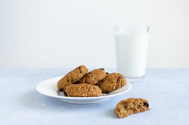 Galletas de avena con pasas y vaso de leche.