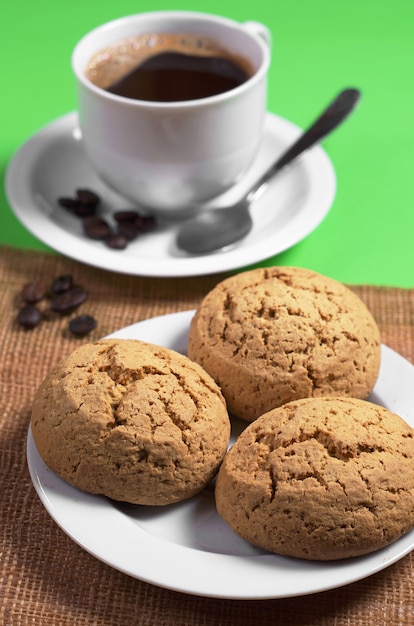 Galletas de avena en plato y taza de café caliente en la mesa