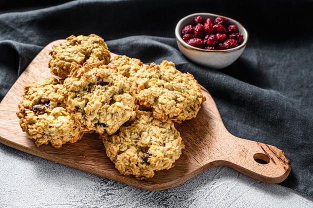 Galletas de avena recién horneadas de arándano en tabla de cortar de madera. Fondo blanco. Vista superior