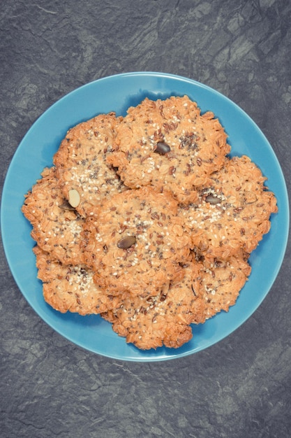 Galletas de avena recién horneadas con miel y semillas saludables en un plato de vidrio azul Delicioso postre crujiente