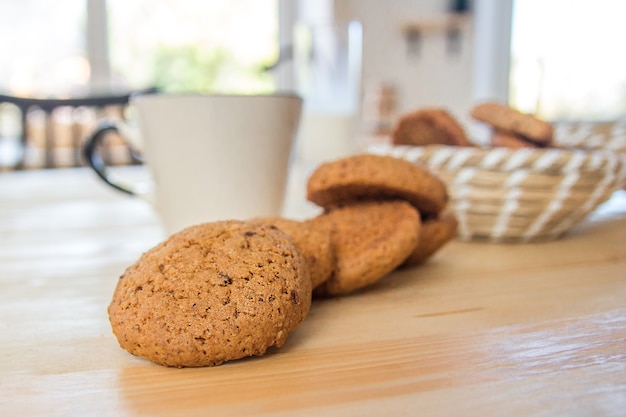 Galletas de avena y una taza de té en una mesa de madera.