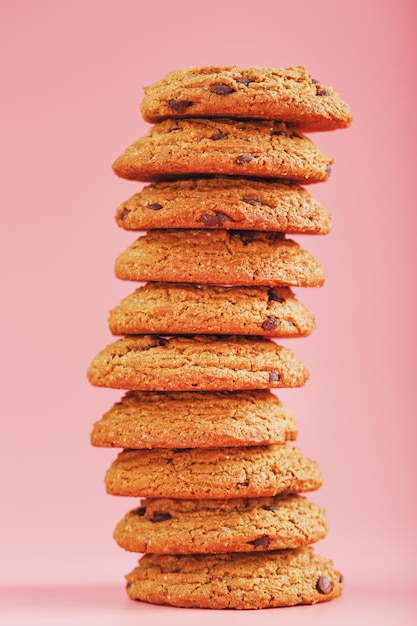 Galletas de avena con trozos de chocolate se colocan como una torre sobre un fondo rosa