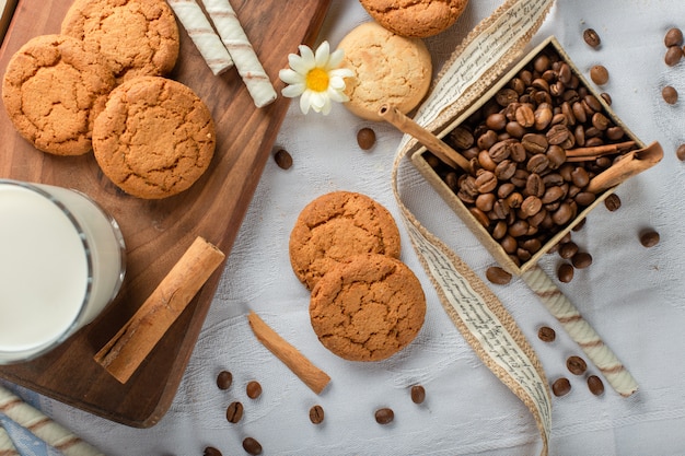 Galletas de avena con un vaso de leche y caja de granos de café. vista superior