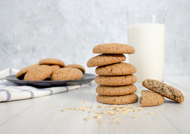 Galletas de avena y un vaso de leche sobre un fondo claro