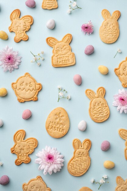 Galletas de azúcar en forma de conejito con huevos de chocolate de Pascua y fondo de flores Felices Pascuas