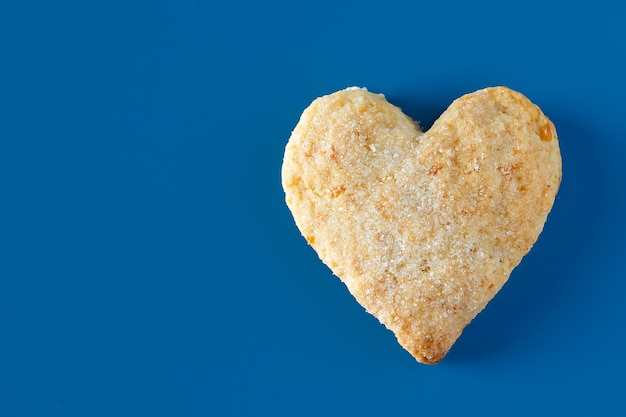 Galletas de azúcar en forma de corazón sobre un fondo azul Una galleta dulce en forma de corazón sobre un fondo azul.