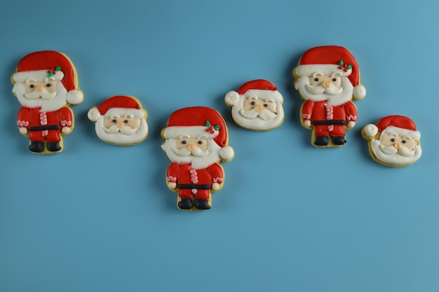 Galletas de azúcar glas de Navidad con forma de Santa Claus con fondo azul.