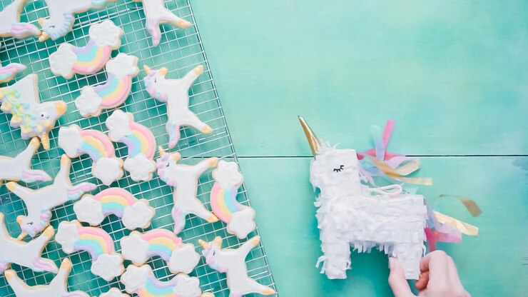 Foto galletas de azúcar de unicornio decoradas con glaseado real sobre fondo azul.