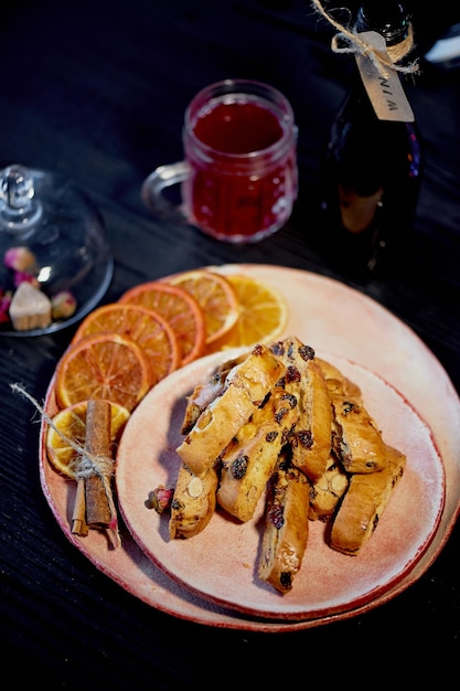 Galletas biscotti sobre un fondo oscuro Una copa de vino tinto o vino caliente