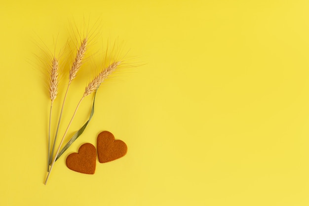 Galletas con canela en forma de corazón, espigas de trigo superficie amarilla