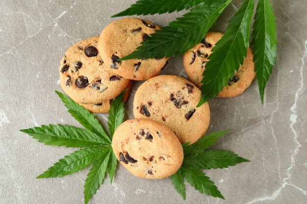 Galletas de cannabis y hojas en mesa con textura gris