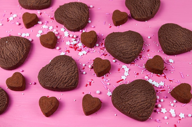 Galletas y caramelos en forma de corazón sobre un fondo de madera rosa. Día de San Valentín.