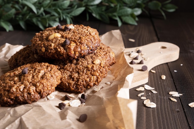 Galletas caseras de avena con chocolate y nueces sobre papel para hornear y una tabla para cortar madera