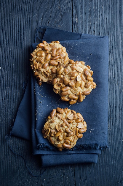 Galletas caseras con cacahuetes sobre mesa de madera negra vista anterior