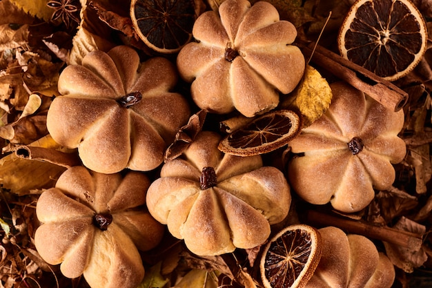 Galletas caseras en forma de calabaza en hojas de otoño. Galletas hechas a mano de Halloween en una mesa, de cerca