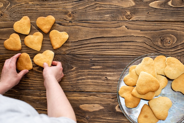 Galletas caseras en forma de corazones. Una persona mueve galletas, pasteles caseros.