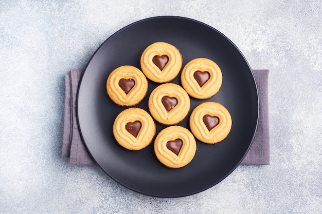 Galletas caseras en forma de corazones en el plato, fondo gris. Concepto de San Valentín. copie el espacio.