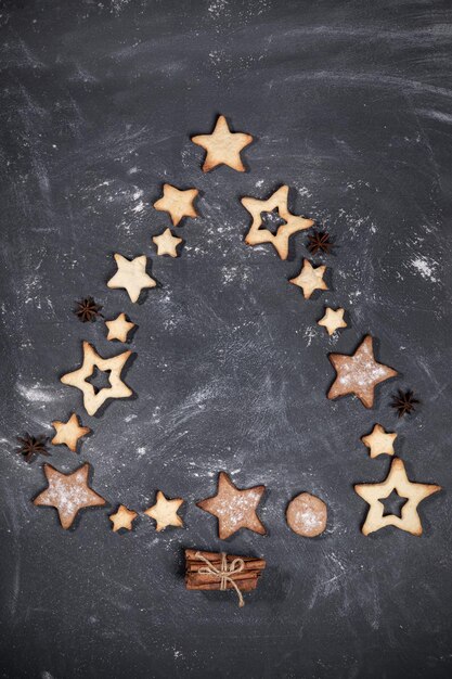 Galletas caseras en forma de estrellas, estrellas de canela y anís en forma de árbol de Navidad en negro.