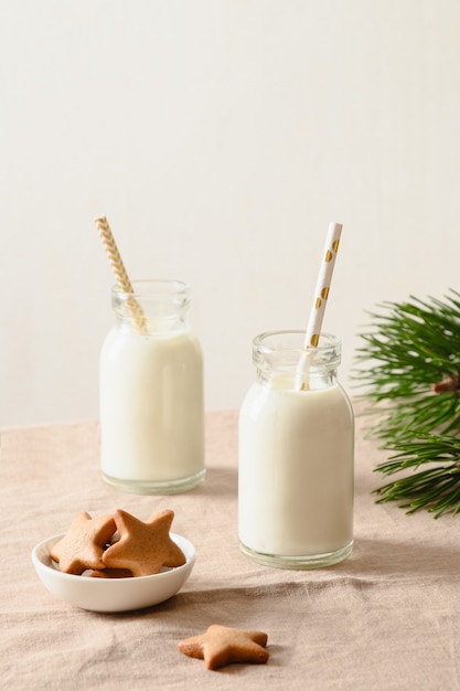Galletas caseras y leche en dos botellas para Santa Claus en la mesa de Navidad
