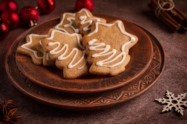 Galletas caseras de pan de jengibre especiadas con glaseado blanco servidas en un plato sobre fondo marrón oscuro