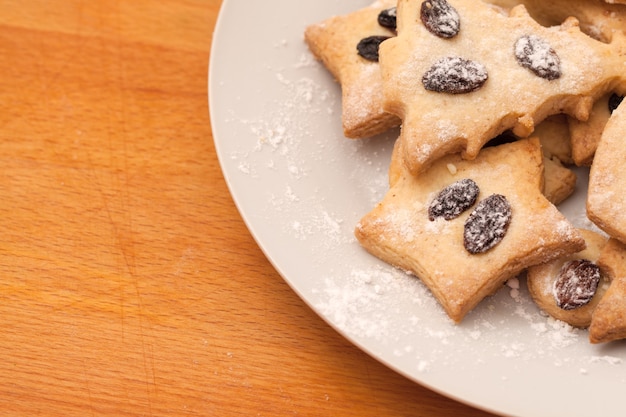 Galletas caseras con pasas sobre la mesa. Formas: círculo, estrella, árbol, corazón.