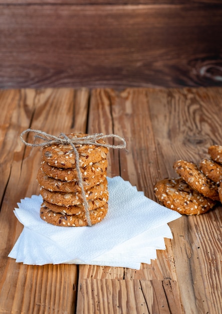 Galletas caseras con trozos de semillas, dispuestas en una pila en el tallo de una mesa de árbol.