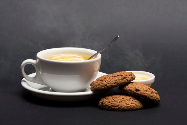 Galletas cerca del té sobre fondo gris oscuro Panadería dulce